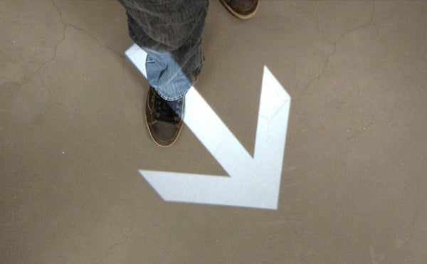 Directional arrow floor projection using One Gobo light projector for indoor navigation.