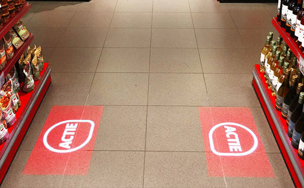 Supermarket aisle with floor projections of ACME logo by One Gobo projector.